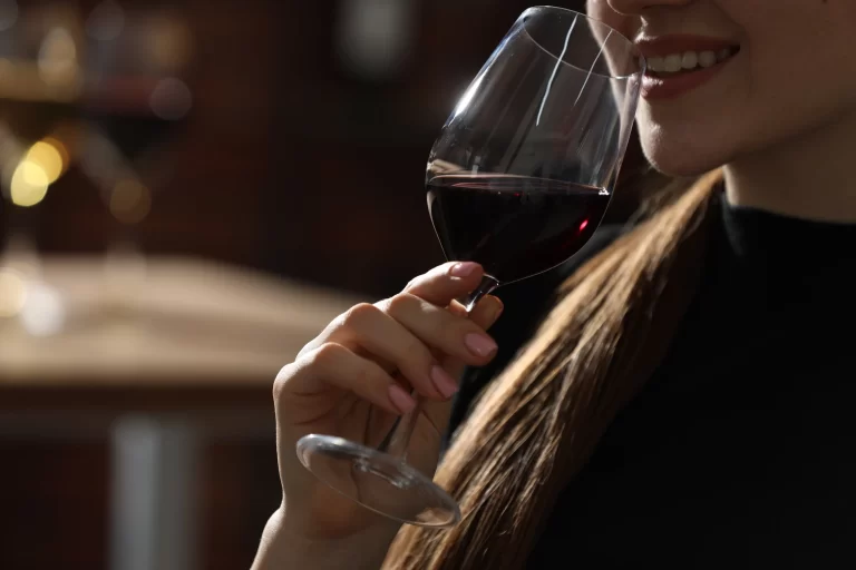 Mujer que disfruta de catas de vinos sorbiendo uno.